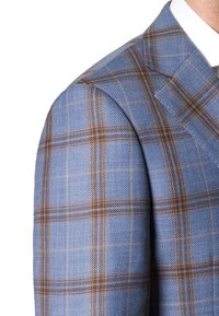 Jasnoniebieska marynarka w kratę, wykonana z teksturowanej tkaniny, z delikatnymi brązowymi i jasnoniebieskimi wzorami w kratę na powierzchni.