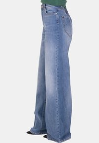 Jeans a gamba larga in denim azzurro chiaro con finitura sbiadita. Presentano cuciture dettagliate e due tasche posteriori. Design classico a cinque tasche.