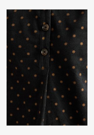 Čierna látková košeľa s malým hnedým hviezdnym vzorom, s gombíkovou légou a textúrovaným povrchom. Viditeľné sú dva hnedé gombíky.