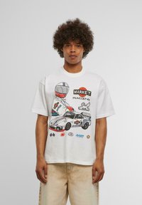 Balta medvilninė t-shirt su spalvinga lenktynių grafika, kurioje pavaizduotas vairuotojas šalmu ir lenktyninis automobilis. Trumpi rankoviai ir laisvas siluetas.