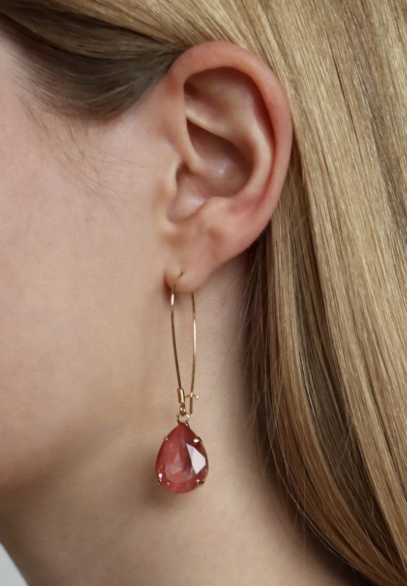Gouden ringoorbel met een druppelvormige rozenkwarts. De edelsteen is facetteerd en stevig gezet met vier klauwen.