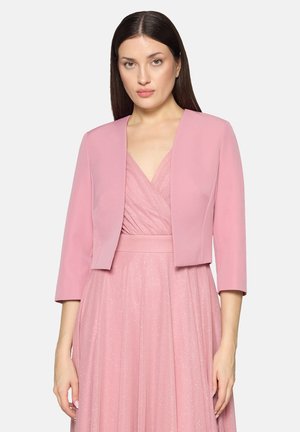 Woman wearing a light pink glittery V-neck dress with a matching solid pink cropped jacket with three-quarter sleeves.