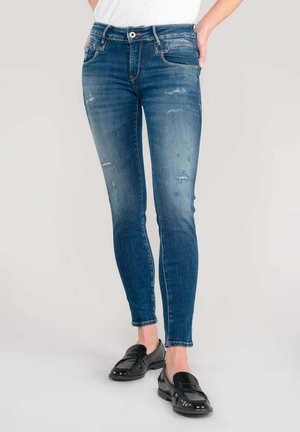 Vaqueros ajustados en denim de azul medio, con un ligero desgastado, detalles rasgados, cinco bolsillos y cierre de cremallera con botón.