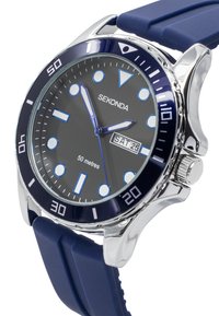 Analog watch with a black dial, silver-tone case, blue bezel, and blue silicone strap. Features luminous markers and date display. Water-resistant to 50m.