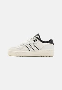 Fehér bőr sneaker fekete részletekkel, perforált mintázattal, háromsávos dizájnnal, kerek orral és texturált gumitalppal.