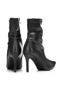 Pár černých kožených kotníkových bot na vysokém podpatku s špičatou špičkou a bočními zipy, zobrazený na bílém pozadí.