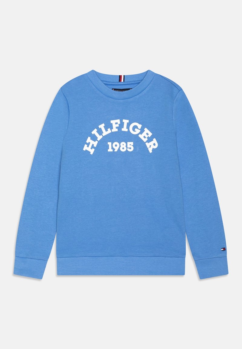 Sweat-shirt bleu clair à manches longues avec col rond, texte blanc "HILFIGER 1985" sur le devant et petit logo sur le poignet de la manche gauche.