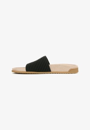 Black slip-on sandal with ribbed fabric strap, beige suede insole, and tan rubber outsole featuring a textured grip pattern.