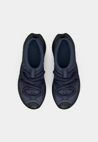 Para ciemnoniebieskich sneakersów z czarnymi podeszwami, grubymi okrągłymi sznurówkami i wyściełanymi wnętrzami, widziana z góry na jednolitym jasnym tle.