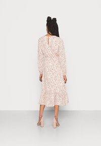 Květinové midi šaty z jemné růžové látky, dlouhé rukávy, vypasovaný pas, rozšířená sukně s volánkem na lemu, s malým otvorem na zádech.