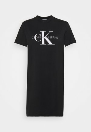 Musta lyhythihainen t-paitamekko, joka on valmistettu puuvillasta. Etuosassa valkoinen "CK" logo ja teksti "CALVIN KLEIN JEANS". Klassinen pyöreä kaula-aukko.