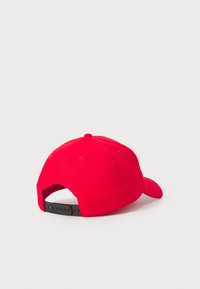 Rød baseballcap med en rund form, der har en sort justerbar rem bagpå og syede øjer for ventilation.