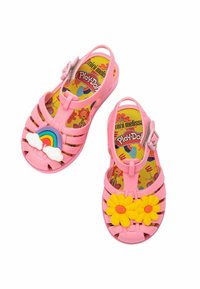 Sandali per bambini di colore rosa, realizzati in materiale flessibile, con un dettaglio di arcobaleno e nuvole su una scarpa e fiori gialli sull'altra.