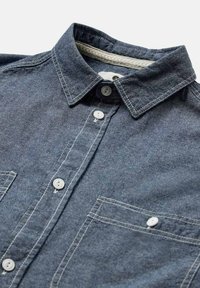 Camicia in denim blu scuro con colletto classico, due tasche frontali e dettagli di cucitura bianca. I bottoni sono circolari e bianchi.