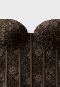 Bustier noir en dentelle sans bretelles avec motifs floraux et baleines verticales, présenté sur un fond uni.