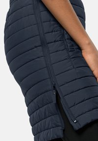 Marineblauwe puffer vest met een gequilt ontwerp, zijrits en contrasterende stoftextuur. Smal fit met een hoge kraag en zonder zichtbare branding.