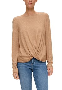 Langärmliges, hellbraunes Strickoberteil mit Rundhalsausschnitt und gedrehtem Frontdetail, kombiniert mit blauen Jeans.