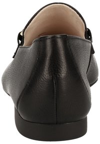 Mocassin noir en cuir sans lacets, vu de dos avec des coutures visibles et une doublure intérieure beige clair.
