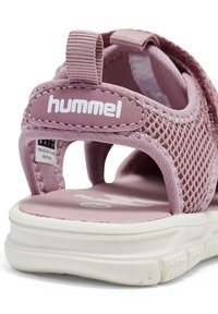 Pink mesh sandal featuring a cushioned white sole, adjustable strap, and a fabric loop at the heel with "hummel" logo.