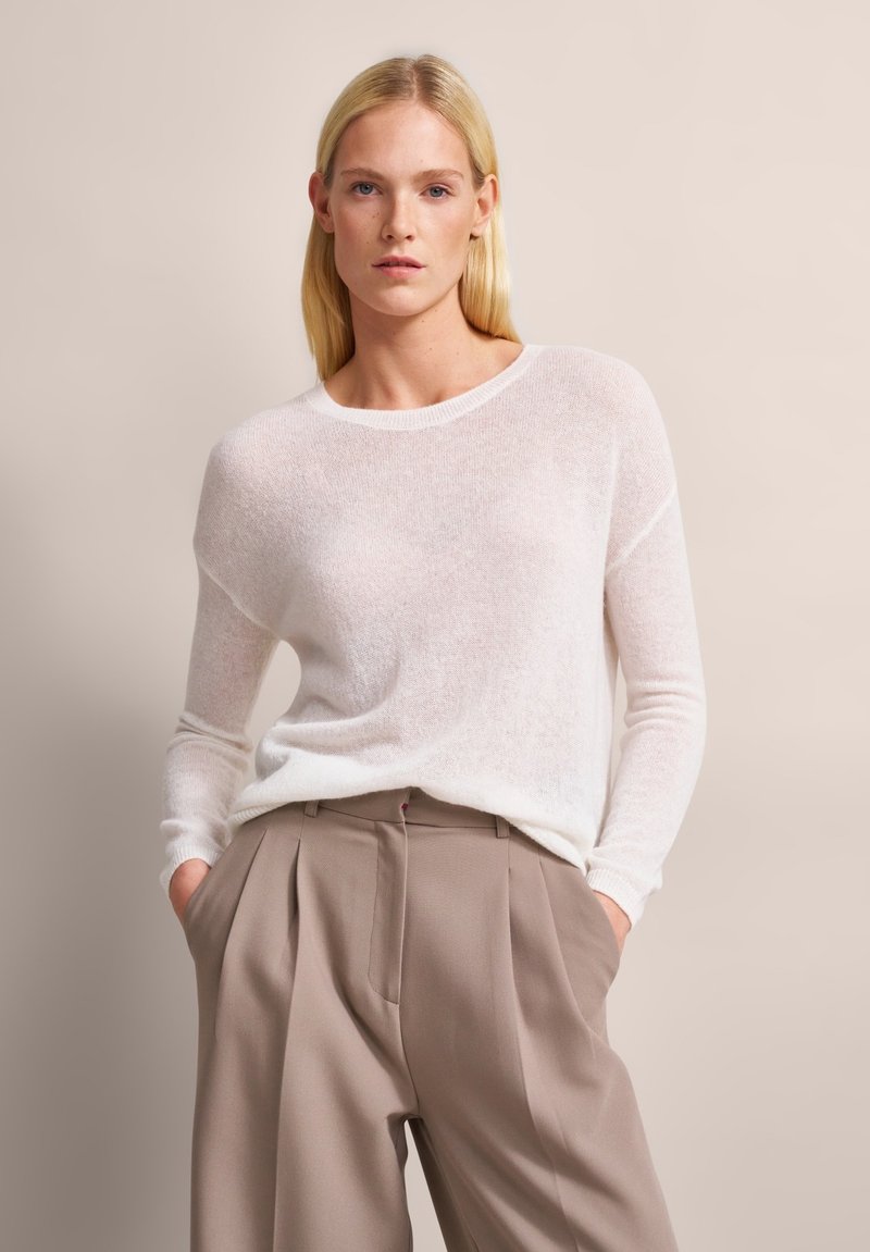 Leichter, cremefarbener Pullover mit Rundhalsausschnitt und langen Ärmeln, kombiniert mit beigen, plissierten Hosen. Weiche Textur, lässige Passform.