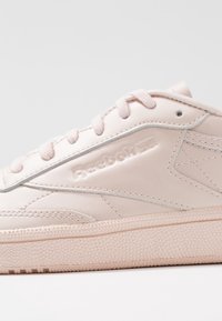 Jasnoróżowy skórzany sneaker z zapięciem na sznurowadła, subtelnymi srebrnymi akcentami i fakturowaną gumową podeszwą, z logo po boku.