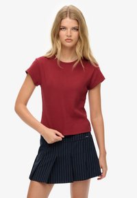 Bordeaux bomulds T-shirt med runde hals og korte ærmer, paired med en marineblå stribet plisseret nederdel. Enkel design og tætsiddende snit.