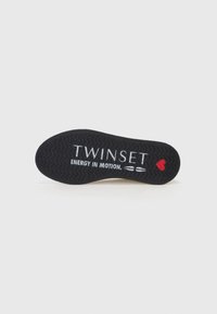 Svart såle med teksturert grep, med "TWINSET" og "ENERGY IN MOTION" i hvitt, aksentuert av en liten rød hjerte-logo.