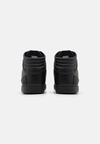 Black high-top sneakers with textured leather, padded collar, and rubber sole. Features embossed logo on the heel and reinforced stitching.