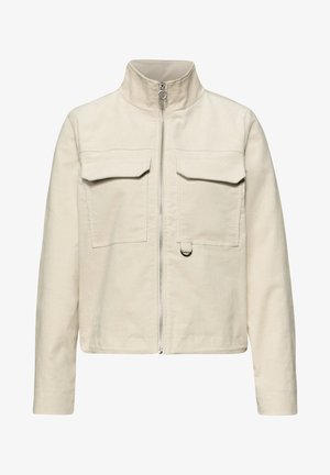 Veste beige en velours côtelé avec col montant, fermeture éclair devant, deux poches poitrine à rabat et un petit détail en anneau métallique sur la poche droite.