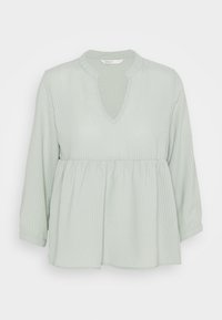 Blusa verde chiaro in tessuto testurizzato, con scollatura a V e orlo plissettato, maniche a tre quarti. Design semplice e casual.