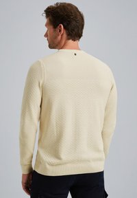 Lichtgele gebreide trui met een ronde hals en lange mouwen. Ribbelmanchetten en -zoom met een klein logodetail bij de halslijn.
