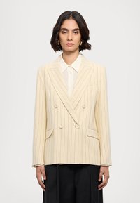 Doppelreihiges Blazer aus cremefarbener Wolle mit schmalen vertikalen Streifen. Verfügt über eine Reverskragen, zwei seitliche Taschen und ein lockeres Design.