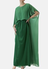 Groene chiffonjurk met een losse silhouet, voorzien van vloeiende mouwen en een getailleerde taille. Soepele textuur en enkelhoge lengte.