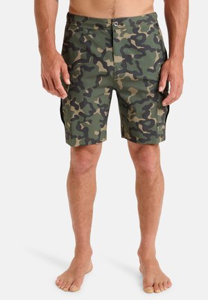 Camouflage board shorts in green, brown, and black. Made of lightweight fabric, feature a button closure, and side pockets.