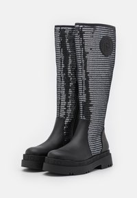 Bottes en caoutchouc noires jusqu'aux genoux avec un design en sequins argentés texturés, présentant un écusson noir et une semelle noire épaisse avec des accents striés.