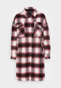 Robe chemise en flanelle à carreaux rouges, noirs, gris et blancs, avec un devant boutonné, un col, et deux poches poitrine. Manches longues.