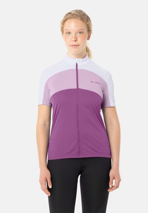 Vrouw draagt een korte mouw, zip-up wielertrui in wit, lichtpaars en donkerpaars, gecombineerd met zwarte wielerbroekjes tegen een witte achtergrond.