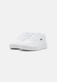 Sneakers bianchi con parte superiore in pelle liscia, suola in gomma testurizzata e design con lacci. Presentano un piccolo logo verde sul lato.