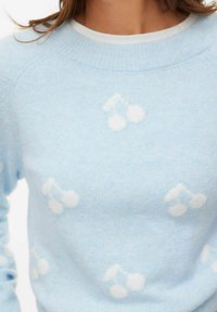 Jasnoniebieski sweter z motywami białych wiśni. Wykonany z miękkiego, teksturowanego materiału, z prążkowanym, okrągłym dekoltem i rękawami typu raglan.