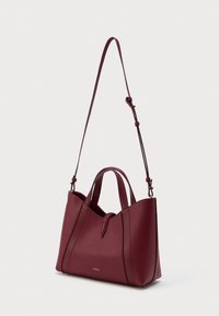 Bordo kožna torba s kratkim dvostrukim ručkama i dugim podesivim remenom za rame, s suptilnim zlatnim logom na prednjoj strani.