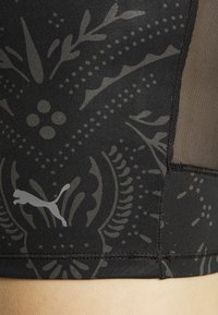 Top desportivo crop preto com um padrão texturizado em cinza escuro, detalhes em malha e um discreto logo da Puma na parte inferior.