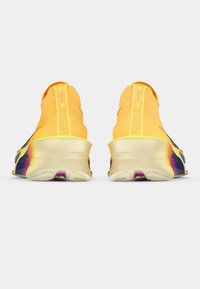 Ryškiai geltonos sportinės bateliai su kojinių tipo viršumi, turinčiu gradientinį pado dizainą su purpuriniais ir žaliais akcentais bei tekstūruotu nugariniu kulnu.