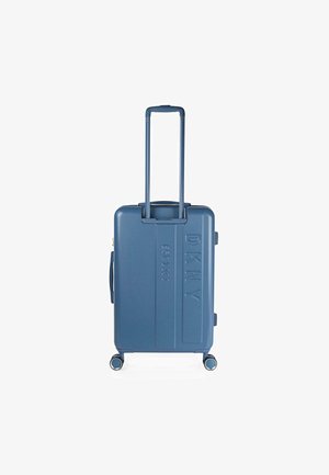 Maleta dura azul con superficie texturizada, logo grabado, asa retráctil y cuatro ruedas para movilidad.