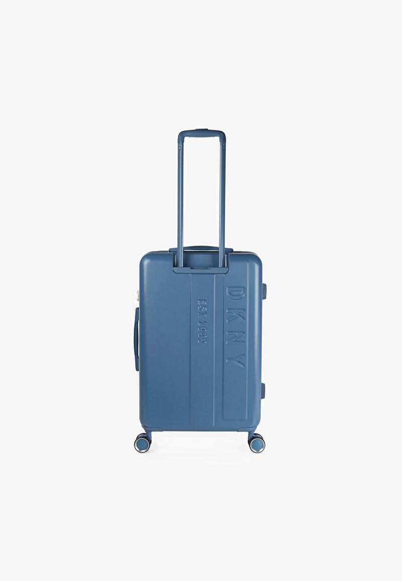Maleta dura azul con superficie texturizada, logo grabado, asa retráctil y cuatro ruedas para movilidad.