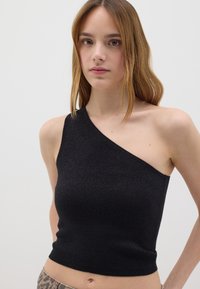 Top nero a spalla unica realizzato in un tessuto testurizzato e stretch. Caratterizzato da un design aderente e una lunghezza cropped, enfatizza la parte superiore del corpo.