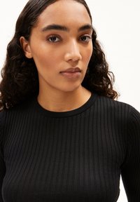 Schwarzes, geripptes Strickoberteil mit Rundhalsausschnitt, das mit Texturdetails und einer taillierten Passform versehen ist, vor einem schlichten weißen Hintergrund gezeigt.