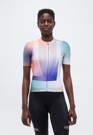 Jong persoon met het gezicht vooruit, draagt een korte mouwen, meerkleurig mesh fietsjersey en zwarte fietsbroek met merktekst op de dijen.