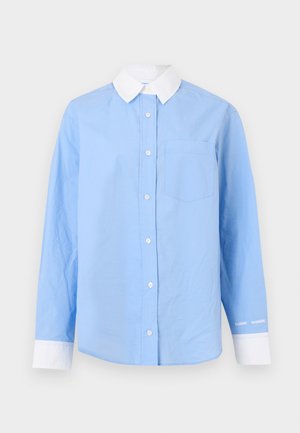 Chemise boutonnée bleu clair avec col blanc, manches longues, poche poitrine et accents de poignets blancs. Tissu en coton doux, design minimaliste.
