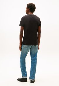 Svart bomulls-t-skjorte med korte ermer, rund hals, lett løs passform. Kombinert med lyseblå jeans og svarte sko. Minimalistisk design.