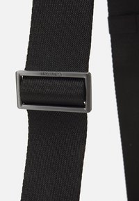 Czarny pleciony pasek o gładkiej fakturze, z prostokątną metalową klamrą w matowym szarym wykończeniu.